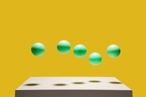 Afbeelding met een tafel waar groene bollen boven zweven. 