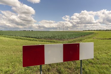 Een verkeersbord op de voorgrond met en een landschap en windmolens op de achtergrond.