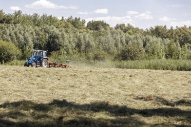 Afbeelding van rijdende tractor op het platteland.