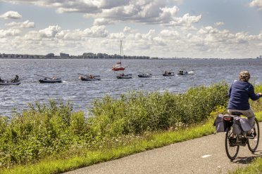 Afbeelding van bootjes in het water en persoon op fiets.