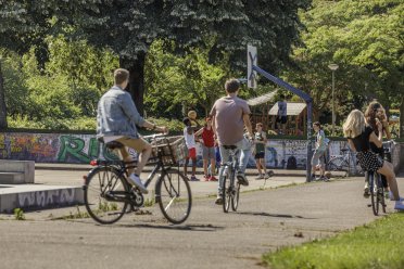 Afbeelding van fietsende kinderen op de voorgrond en basketballende kinderen op de achtergrond.